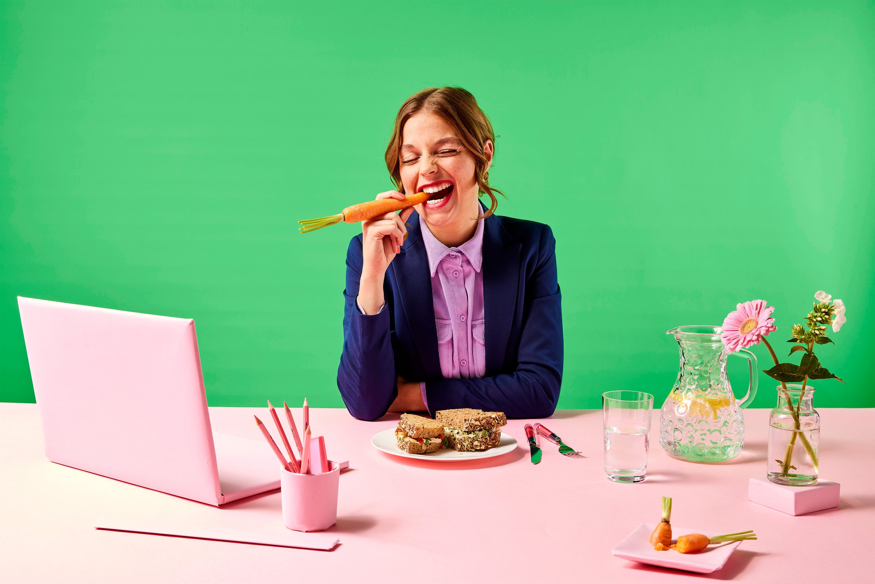 vrouw eet wortel in kleurrijke kantoorsetting, yummiz, vegetarisch